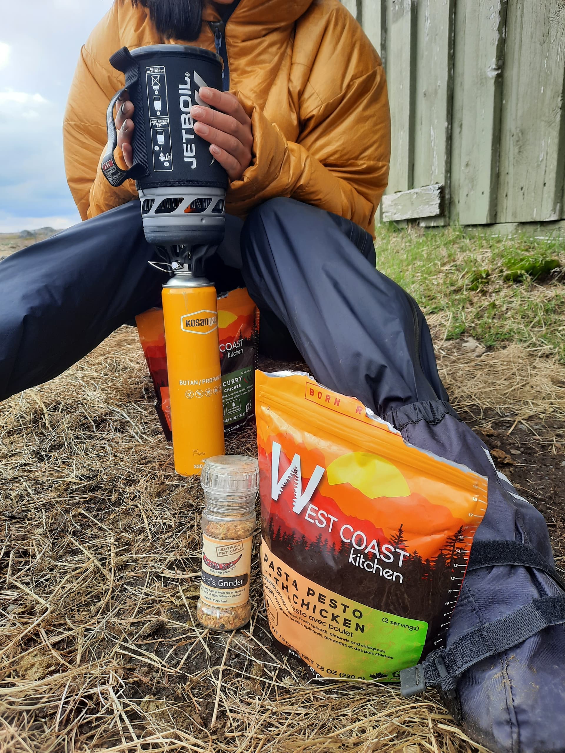 Person in orange jacket cooking WCK Pasta Pesto with Chicken using a Jetboil